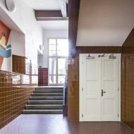 ADEL Halbrunde Wandlampe aus Opalglas Beleuchtung eines Schulflurs.