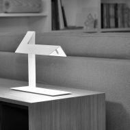 PLI LED table lamp made of folded sheet aluminum in white or black Als Bestellleuchte im Wohnraum.